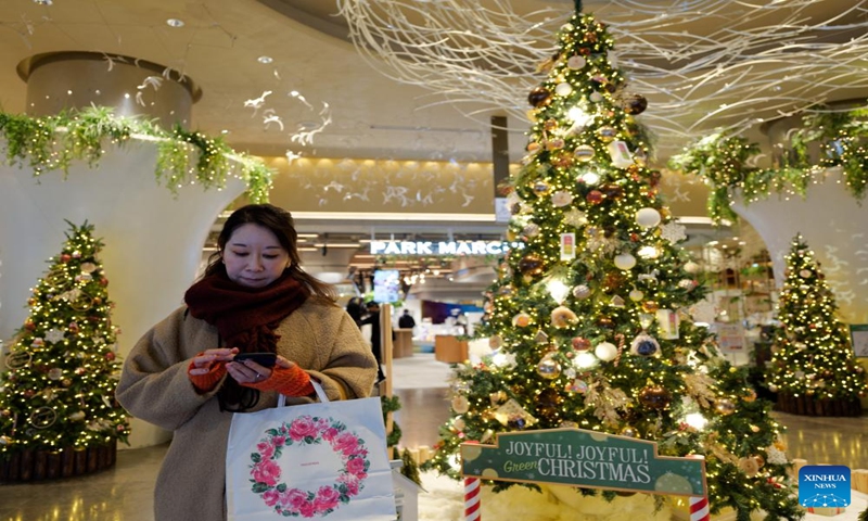 A woman shops at a mall decorated with Christmas trees in Yurakucho, Tokyo, Japan, Dec. 24, 2023. (Xinhua/Zhang Xiaoyu)