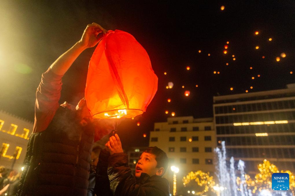 People release sky lanterns at Kotzia square in Athens, Greece, Dec. 24, 2023. The sky of Athens was lit up by sky lanterns carrying people's good wishes on Christmas Eve during the Night of the Wishes event which was held here for the second consecutive year.(Photo: Xinhua)