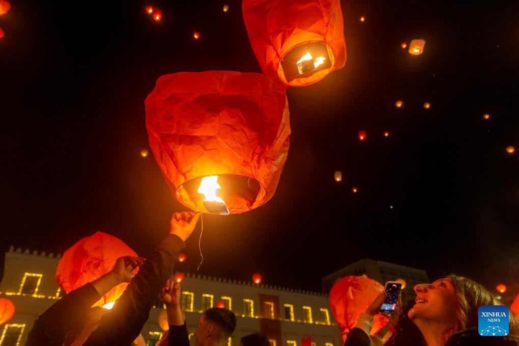 People release sky lanterns at Kotzia square in Athens, Greece, Dec. 24, 2023. The sky of Athens was lit up by sky lanterns carrying people's good wishes on Christmas Eve during the Night of the Wishes event which was held here for the second consecutive year.(Photo: Xinhua)