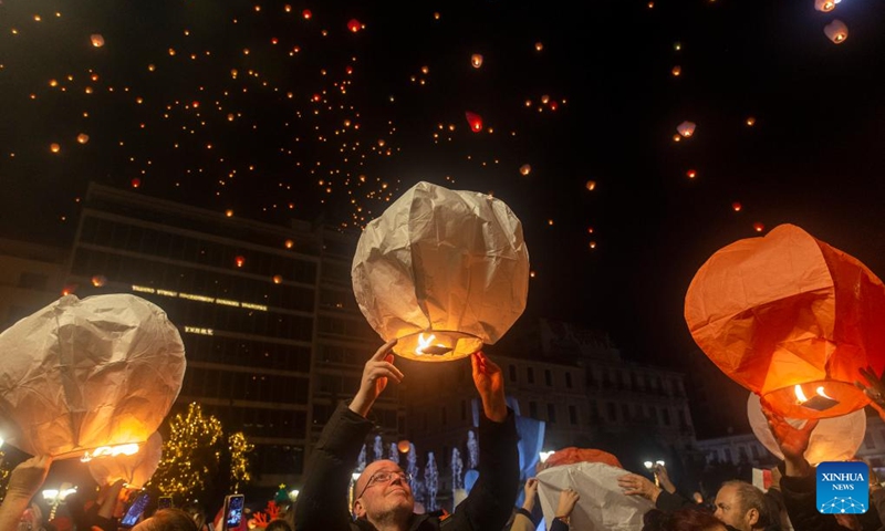 People release sky lanterns at Kotzia square in Athens, Greece, Dec. 24, 2023. The sky of Athens was lit up by sky lanterns carrying people's good wishes on Christmas Eve during the Night of the Wishes event which was held here for the second consecutive year.(Photo: Xinhua)