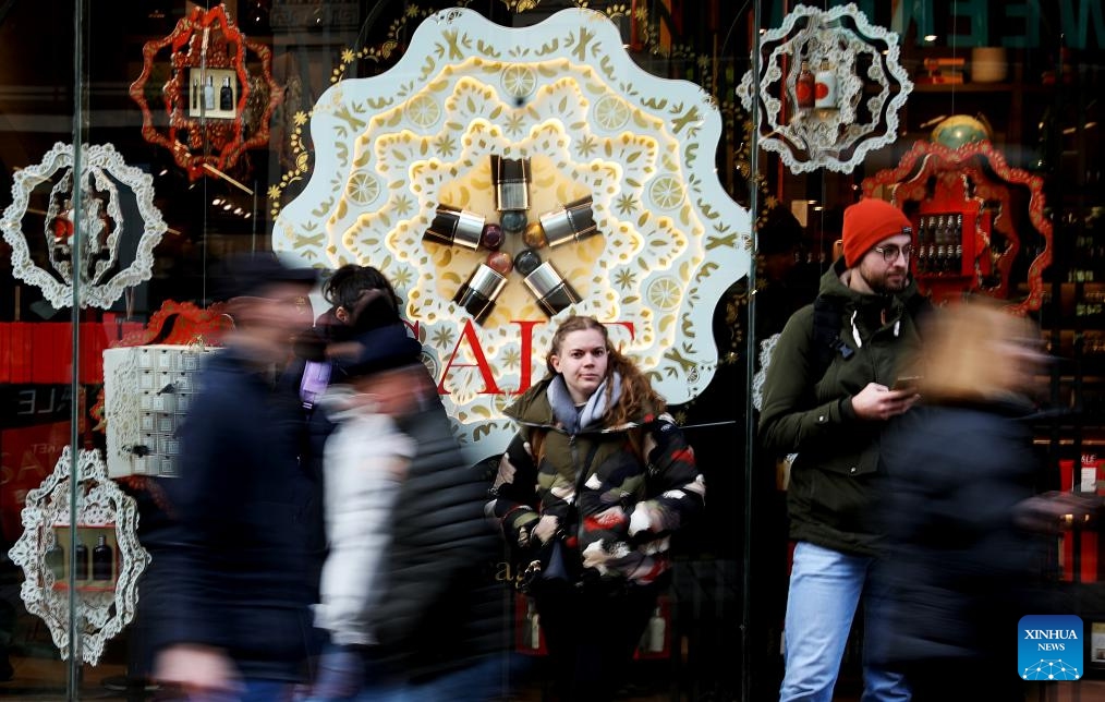 A woman stands in front of a sale sign outside a store during Boxing Day sales in London, Britain, on Dec. 26, 2023.(Photo: Xinhua)