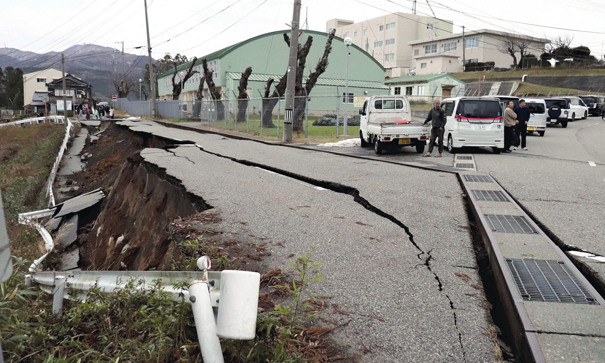 People stand next to large cracks in the pavement after evacuating into a street in the city of Wajima, Ishikawa prefecture, Japan on January 1, 2024, after a major 7.4 magnitude earthquake struck the Noto region in Ishikawa prefecture in the afternoon. Photo: AFP 