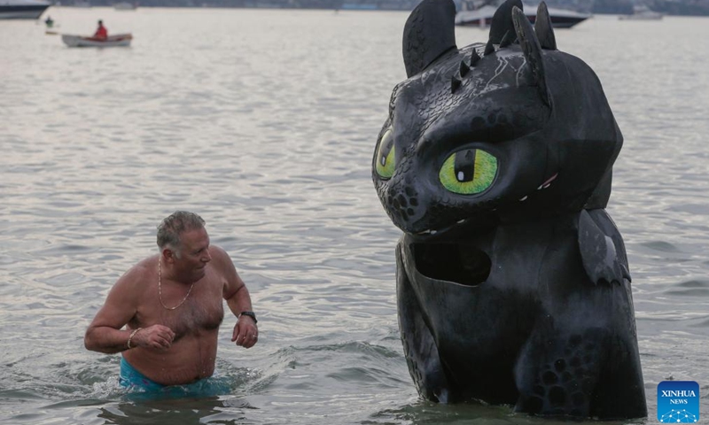 A person in dinosaur costume (R) participates in the 104th annual Polar Bear Swim at English Bay in Vancouver, British Columbia, Canada, on Jan. 1, 2024. (Photo: Xinhua)