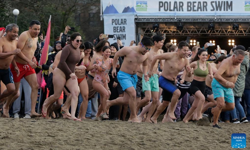 People dash to the water during the 104th annual Polar Bear Swim at English Bay in Vancouver, British Columbia, Canada, on Jan. 1, 2024. (Photo: Xinhua)