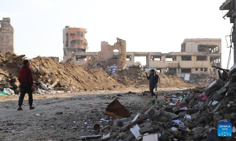 People walk past destroyed buildings in Gaza City, on Jan. 2, 2024. The death toll of Palestinians has exceeded 22,000 after the outbreak of the Israel-Hamas conflict on Oct. 7, 2023, the Hamas-run Health Ministry said on Tuesday. (Photo: Xinhua)