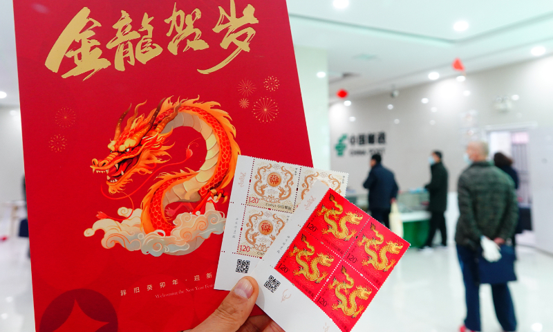 A buyer shows off special zodiac stamps, related commemorative envelopes and greeting cards in Yichang, Central China's Hubei Province, on January 5, 2024. The year 2024 is the Year of the Dragon in the Chinese calendar. The zodiac stamps were released on January 5 by China Post. Photo: VCG