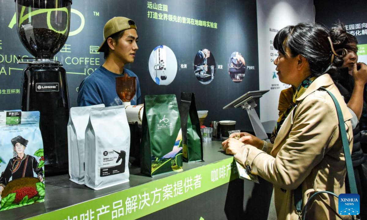 An exhibitor (L) introduces coffee products to a customer during China (Pu'er) International Coffee Expo in Pu'er, southwest China's Yunnan Province, Jan 5, 2024. Photo:Xinhua