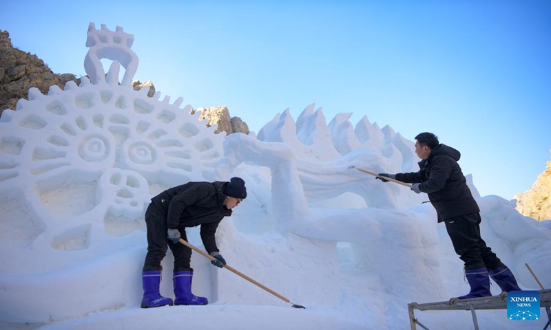 Staff members create a snow sculpture at the cliff painting scenic area of Helan Mountain in northwest China's Ningxia Hui Autonomous Region, Jan. 5, 2024. (Xinhua/Feng Kaihua)