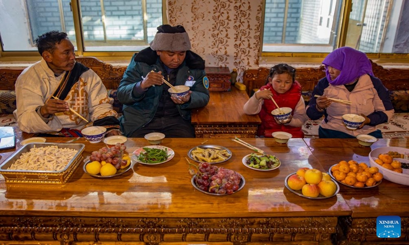 Villager Tsering Chodar (1st L) has dinner at home in the remote Beiga No.4 Village in Xainza County, southwest China's Xizang Autonomous Region, Jan. 5, 2024. The fruits and vegetables on the table were all purchased at the direct sales store in the village after being delivered there by Xainza County's Supply and Marketing Cooperative on the same day.(Xinhua/Jiang Fan)