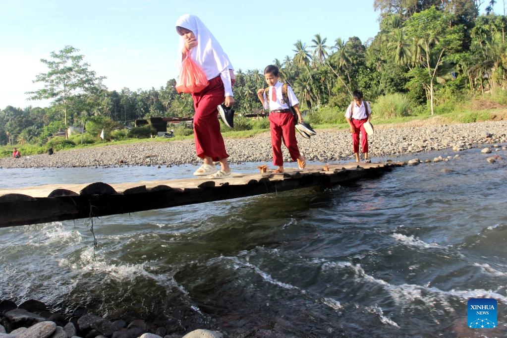 Students walk on a temporary wooden bridge on the way to school at a village in West Sumatra, Indonesia, Jan. 8, 2024.(Photo: Xinhua)