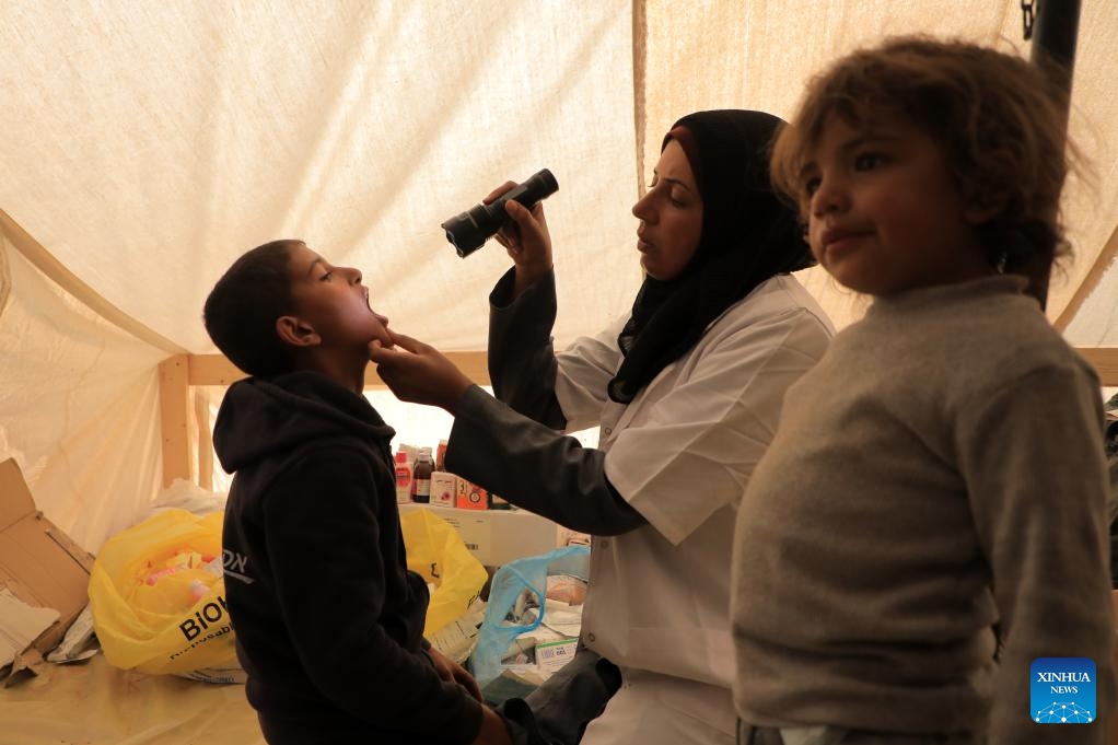 A doctor checks the condition of a boy at a temporary clinic in the southern Gaza Strip city of Rafah, on Jan. 8, 2024. Israel has been fighting with Hamas in the Gaza Strip since Oct. 7, 2023, after the Palestinian faction launched a surprise attack on southern Israel that killed about 1,200 people. The Israeli army has so far killed more than 23,000 Palestinians in its military operations in the enclave, the Gaza-based Health Ministry said Monday.(Photo: Xinhua)