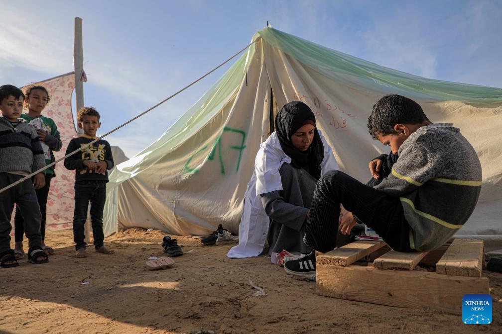 A doctor checks the condition of a boy at a temporary clinic in the southern Gaza Strip city of Rafah, on Jan. 8, 2024. Israel has been fighting with Hamas in the Gaza Strip since Oct. 7, 2023, after the Palestinian faction launched a surprise attack on southern Israel that killed about 1,200 people. The Israeli army has so far killed more than 23,000 Palestinians in its military operations in the enclave, the Gaza-based Health Ministry said Monday.(Photo: Xinhua)