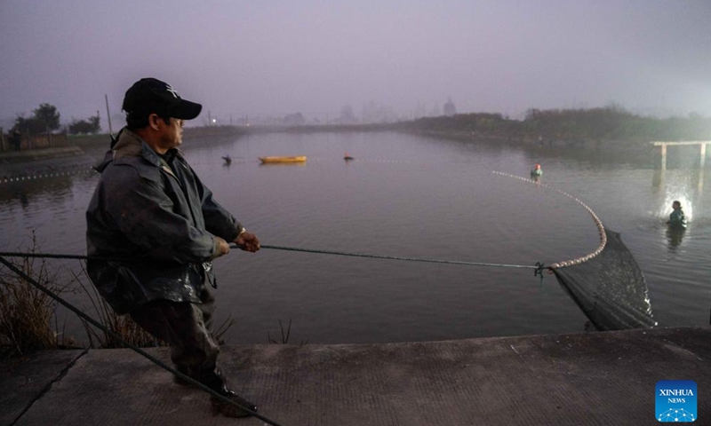 A fisherman catches fishes in Yanhedi Village, Nanxian County, central China's Hunan Province, Jan. 13, 2024. Nanxian County saw busy winter fish catching by local fishermen at present to meet the demand of the market. The annual output of aquatic products in the county reached 162,000 tons in 2023. (Xinhua/Chen Sihan)