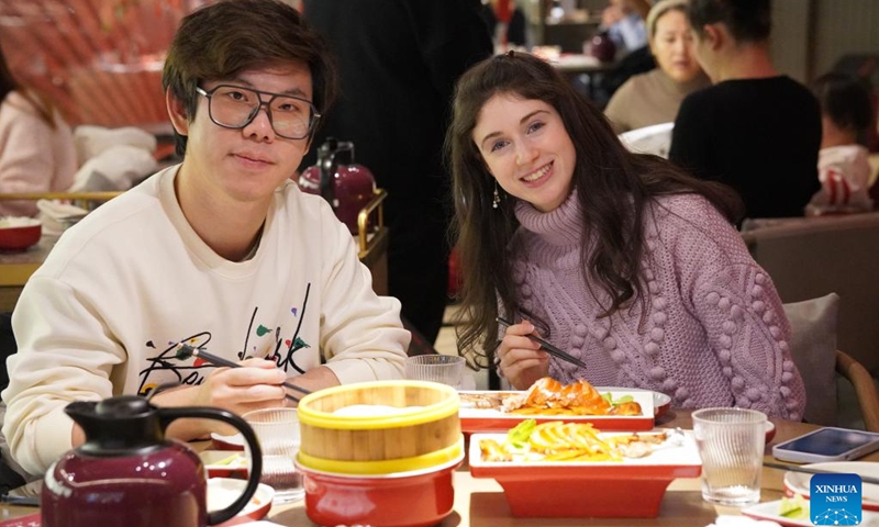 Carly Beth tastes Beijing Roast Duck with producer Wang Ruixing in Beijing, capital of China, Jan. 17, 2024.(Photo by Debbie Lynn/Xinhua)