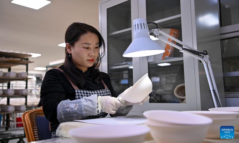 A craftswoman checks a ceramic body at a production base of Honglyucai (Red and Green Color) Porcelain in Honglyucai Village, Changzhi City of north China's Shanxi Province, Jan. 3, 2024. (Xinhua/Yang Chenguang)