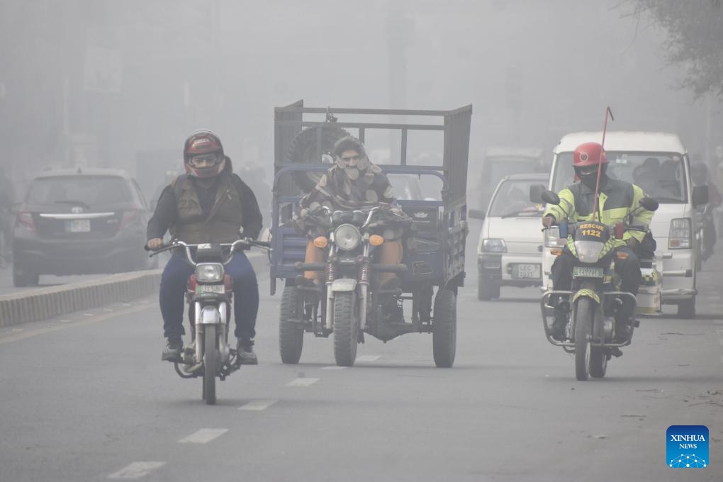 People and vehicles are seen on a road in heavy fog in Lahore, Pakistan on Jan. 17, 2024(Photo: Xinhua)