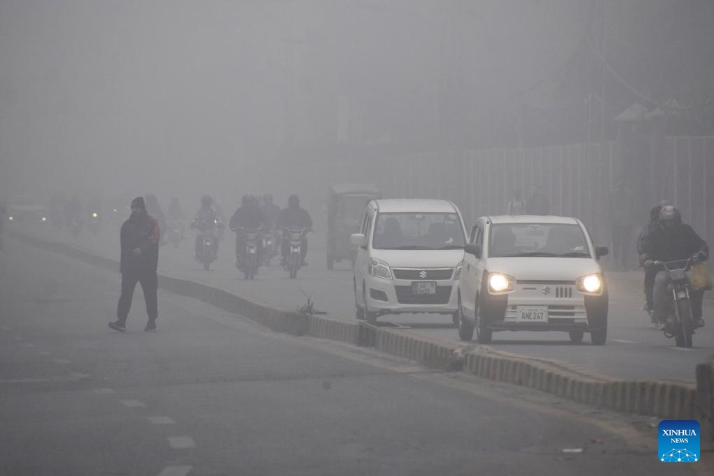 People and vehicles are seen on a road in heavy fog in Lahore, Pakistan on Jan. 17, 2024(Photo: Xinhua)