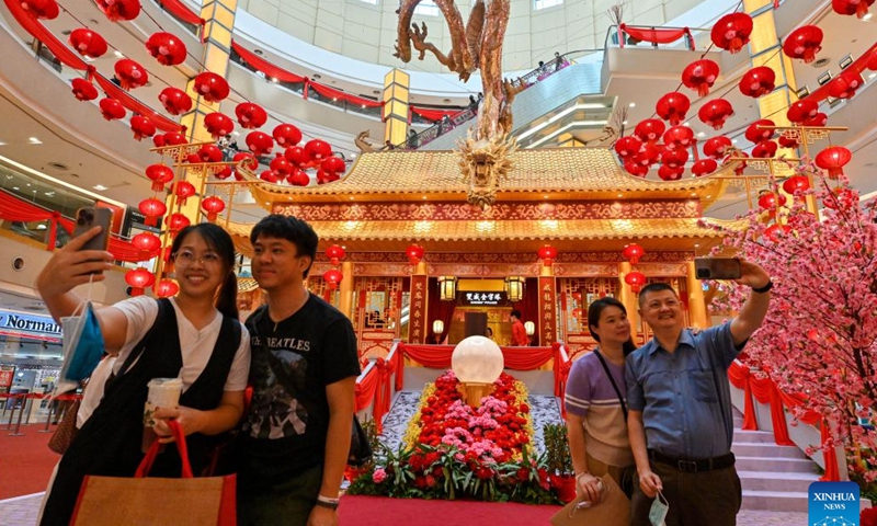 People pose for selfies with a dragon-shaped installation in celebration of the upcoming Chinese zodiac Year of the Dragon at a shopping mall in Kuala Lumpur, Malaysia, on Jan. 18, 2024. (Photo by Chong Voon Chung/Xinhua)