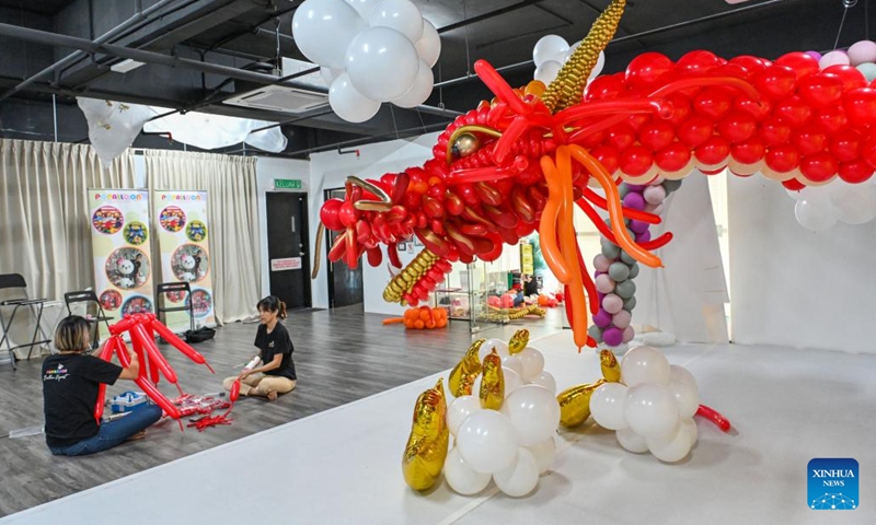 Syndy Tan (L) uses balloons to build a dragon-shaped installation in Kuala Lumpur, Malaysia, on Jan. 18, 2024. In celebration of the upcoming Chinese zodiac Year of the Dragon, Tan, who is good at balloon creations, has used over 600 balloons to build the vivid dragon. (Photo by Chong Voon Chung/Xinhua)