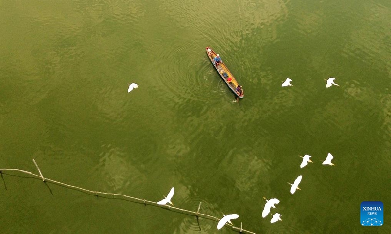 An aerial drone photo taken on Jan. 18, 2024 shows a fisherman rowing a wooden boat near floating fish farms in Lhokseumawe, Aceh Province, Indonesia. (Photo by Fachrul Reza/Xinhua)