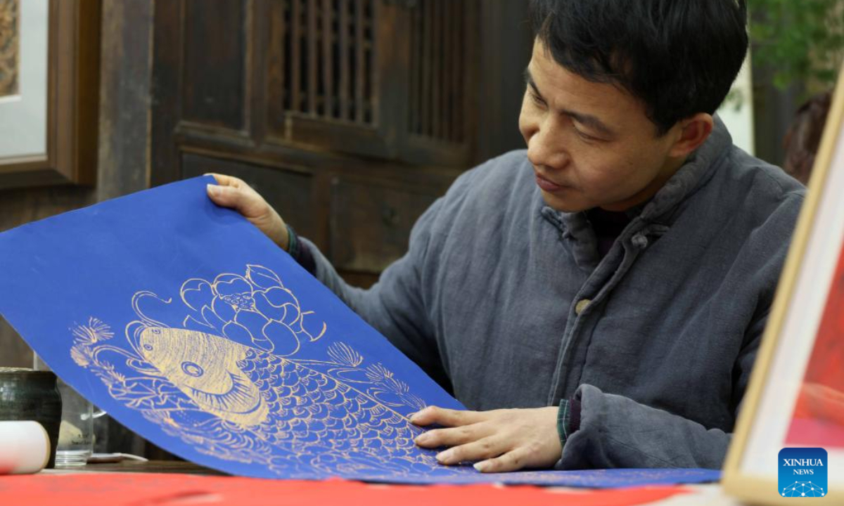 Tong Min looks at a copy of woodcut New Year painting at a studio in Hefei, east China's Anhui Province, Feb 4, 2024. Photo:Xinhua