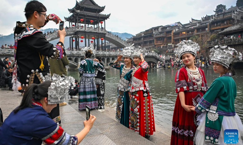 Tourists in costumes pose for photos at Fenghuang ancient town in Xiangxi Tujia and Miao Autonomous Prefecture, central China's Hunan Province, Feb. 14, 2024. More Chinese people nowadays choose to go on a journey during the Spring Festival to experience different cultures and lunar new year atmosphere. (Photo by Guo Liliang/Xinhua)