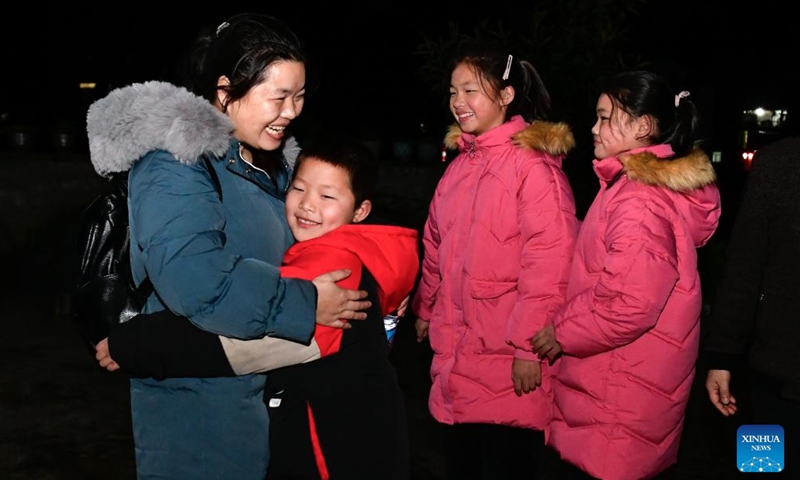 Long Chunxiang (1st L) hugs her son in Ladong Village of Jinping County, southwest China's Guizhou Province, Feb. 1, 2024.