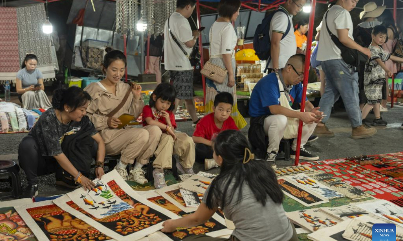 Tourists buy handicraft products at a fair in Luang Prabang, Laos, Feb. 16, 2024. The China-Laos Railway is witnessing its first Spring Festival travel rush since the railway started cross-border passenger services on April 13, 2023. Laos embraced a boost in tourism thanks to the passenger flow brought by the China-Laos Railway during the Spring Festival holiday. (Photo by Kaikeo Saiyasane/Xinhua)