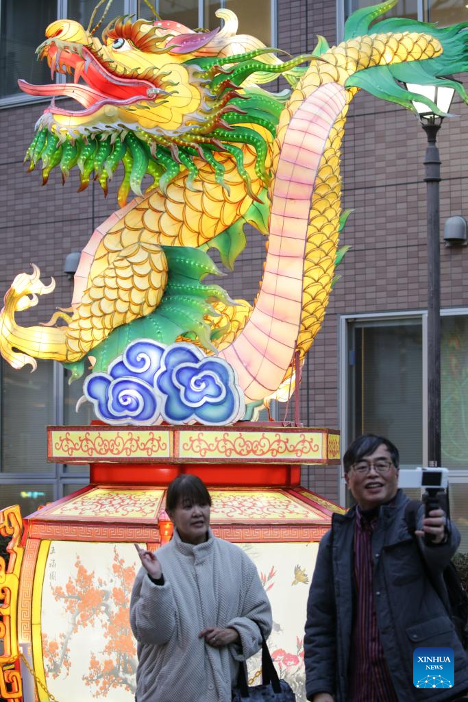 Tourists pose for photos with lanterns in the Chinatown of Yokohama, Japan, Feb. 11, 2024. Tourists came to the Chinatown to enjoy festive atmosphere of the Spring Festival. (Xinhua/Yue Chenxing)