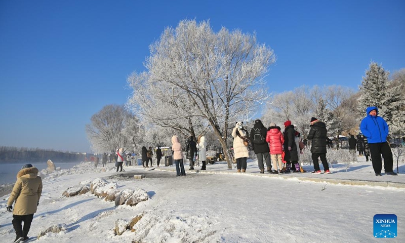 Tourists enjoy the rime scenery along a river in Jilin City, northeast China's Jilin Province, on Jan. 26, 2024. Boasting abundant ice and snow resources, Jilin Province in northeast China continues to optimize its tourism service to gain prominence as one of the most popular winter destinations for tourists. (Xinhua/Chen Yehua)