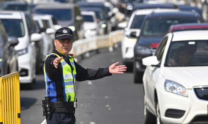 A police officer direct traffic near a port in Haikou, south China's Hainan Province, Feb. 17, 2024. Qiongzhou Strait witnessed a peak of travel rush of returning passengers on Feb. 17, the last day of the Spring Festival holiday.

Various actions were taken by local authorities to ensure passengers to cross the strait in an orderly manner including organizing personnel to maintain the queuing order, providing emergency medicines, drinking water and other supplies to drivers and tourists. (Xinhua/Guo Cheng)