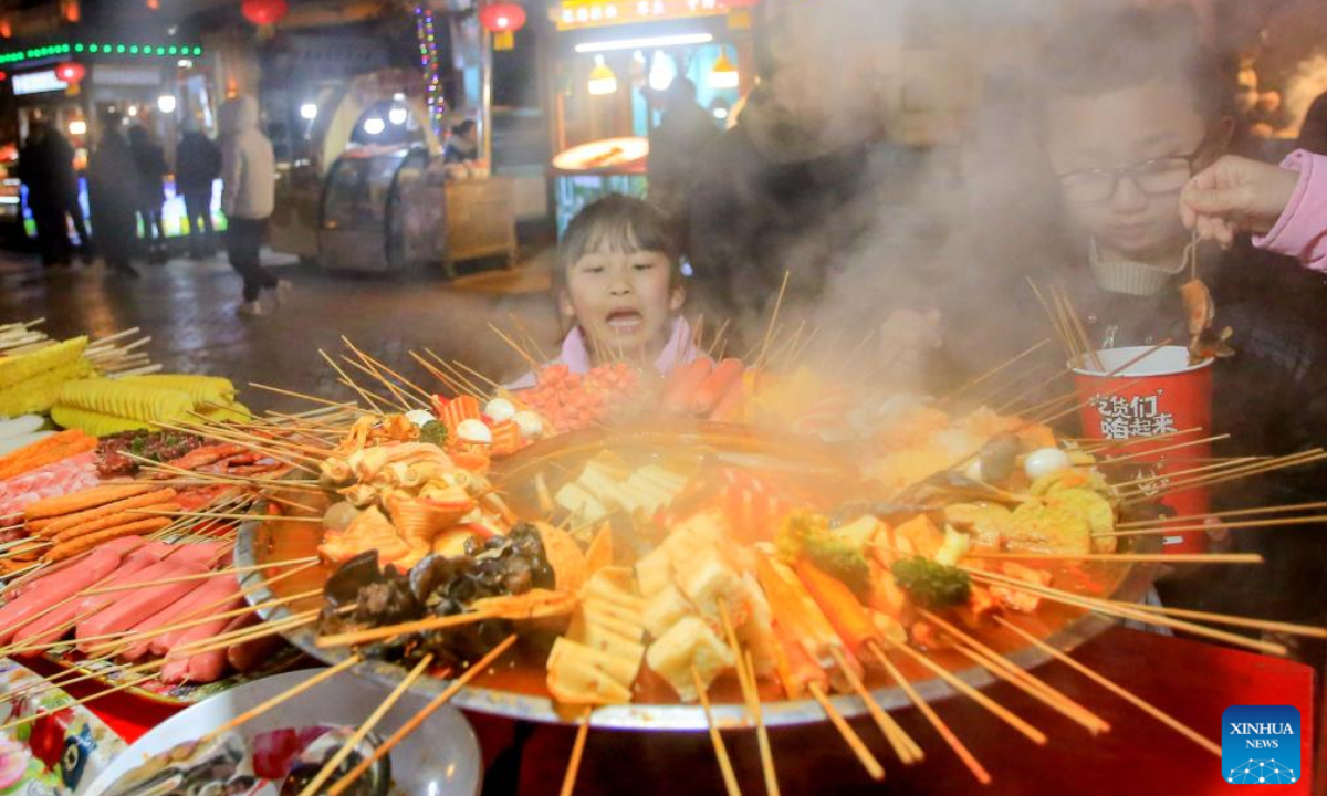 Children eat snacks at a night market in the ancient city of Kashgar, northwest China's Xinjiang Uygur Autonomous Region, Feb 4, 2024. Photo:Xinhua