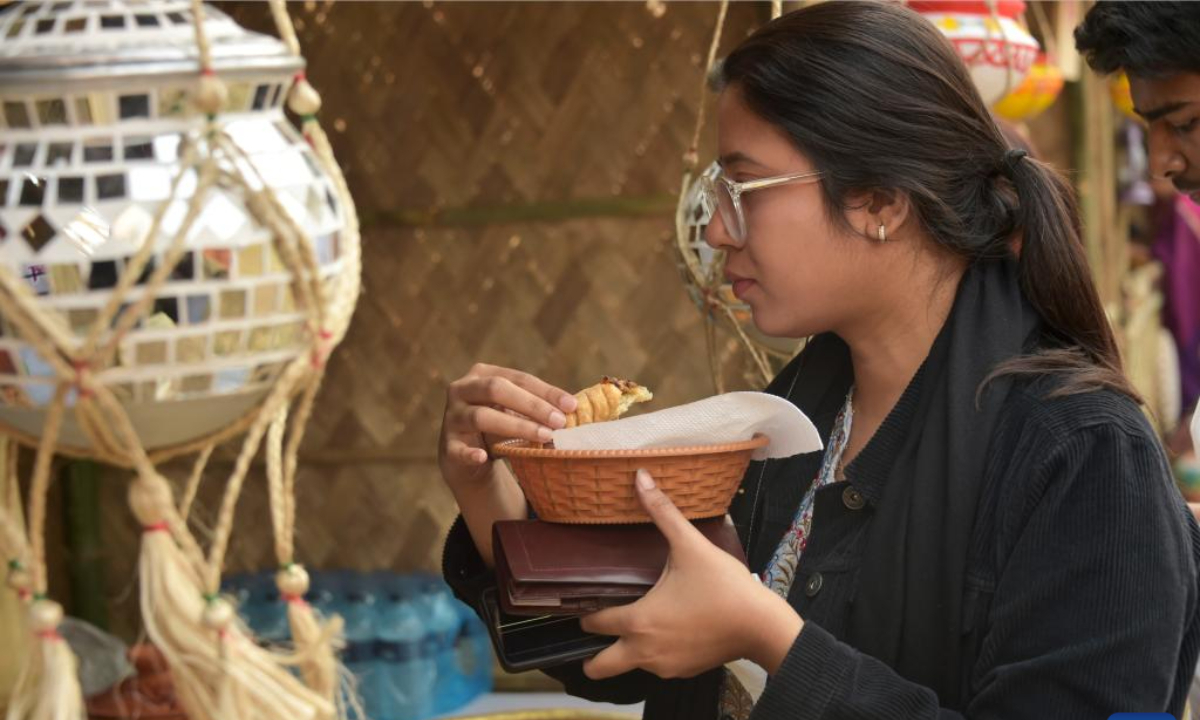 A woman eats a type of Pitha during a festival in Dhaka, Bangladesh, Jan 31, 2024. Photo:Xinhua