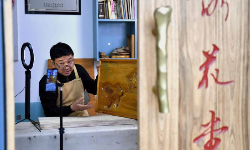 Craftsman Cui Jianjun presents his wood carvings via live streaming in Feixiang District, Handan City, north China's Hebei Province, Feb. 19, 2024. During the Spring Festival, a series of live streaming events were held in Feixiang District of Handan, introducing the Chinese intangible cultural heritages like eggshell carving and wood carving to netizens. (Xinhua/Wang Xiao)