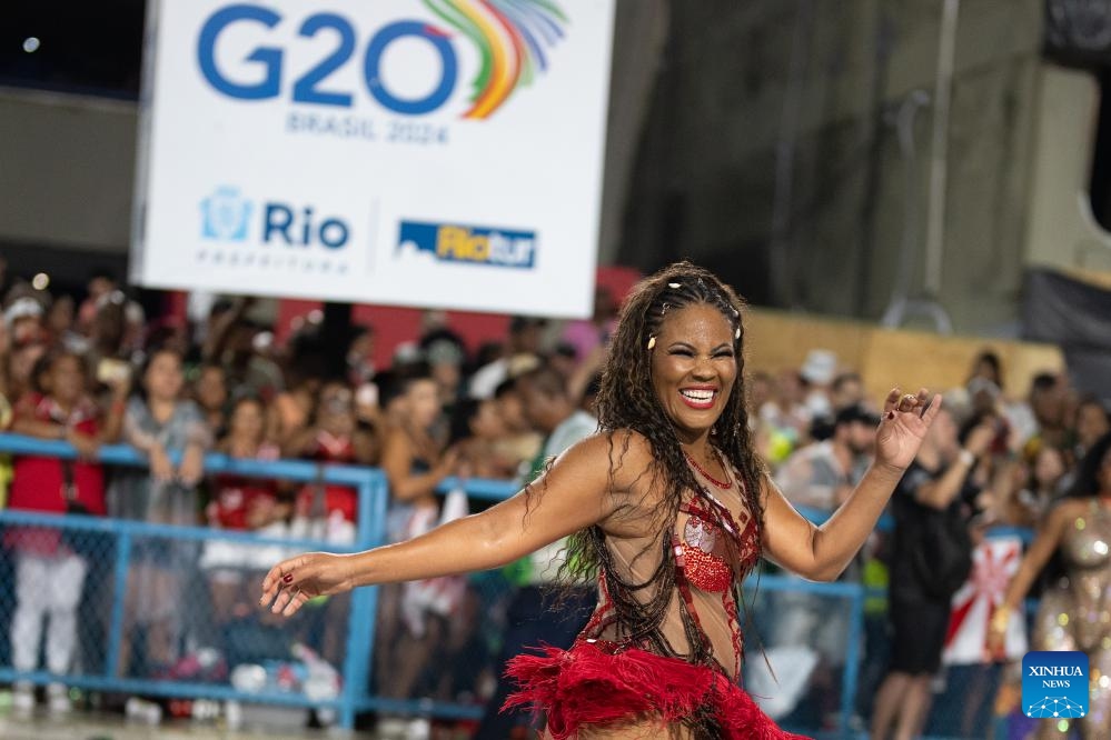 A performer participates in a carnival parade rehearsal in front of a poster featuring the 'G20' logo in Rio de Janeiro, Brazil, Jan. 21, 2024.(Photo: Xinhua)