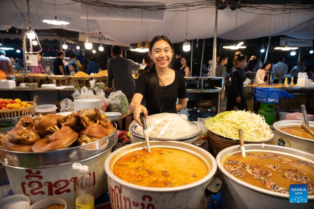 A vendor sells food during Lao Food Festival in Vientiane, capital of Laos on Jan. 23, 2024. The annual Lao Food Festival is held here from January 23 to 27.(Photo: Xinhua)