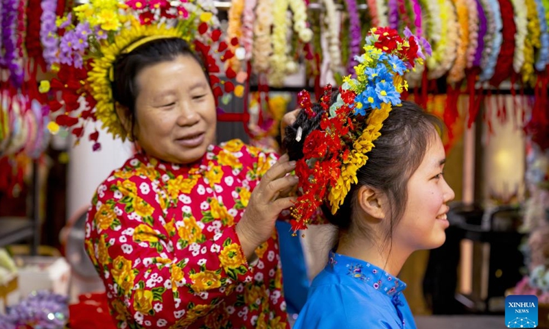 A villager pins a flowery headwear for a tourist at Xunpu Village of Quanzhou City, southeast China's Fujian Province, Jan. 26, 2024. (Xinhua/Wei Peiquan)