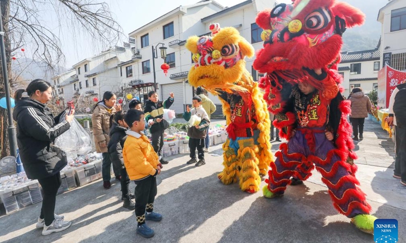 Tourists and villagers watch lion dance during a Chinese New Year culture festival in Lianhua Town of Jiande City, east China's Zhejiang Province, Jan. 28, 2024. A culture festival celebrating the upcoming Chinese New Year is held in Lianhua Town on Sunday. Tourists enjoyed watching traditional performances while having delicacies at a large open-air banquet consisted of 100 tables amid a bustling and festive atmosphere. (Xinhua/Xu Yu)