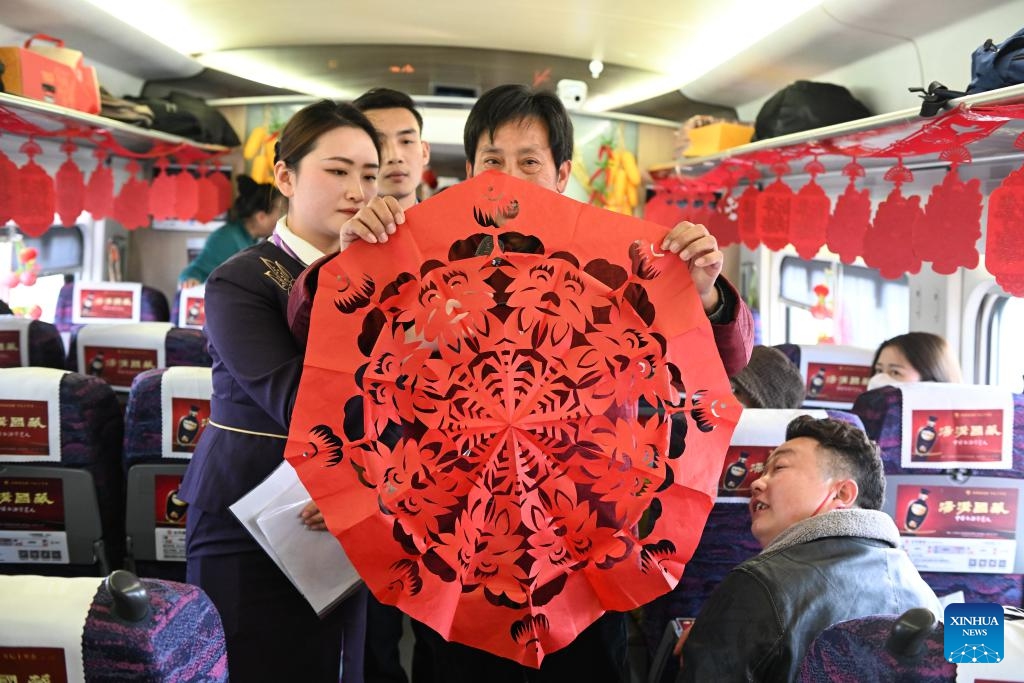 A craftsman shows a piece of paper cutting work onboard G7575 bullet train, Jan. 29, 2024. A series of traditional cultural activities, such as opera performance and paper cutting show, were held on the bullet train on Monday. China officially ushered in its largest annual population migration on Jan. 26. The 40-day travel surge, also known as chunyun, will see hundreds of millions of people return home and reunite with their friends and families.(Photo: Xinhua)