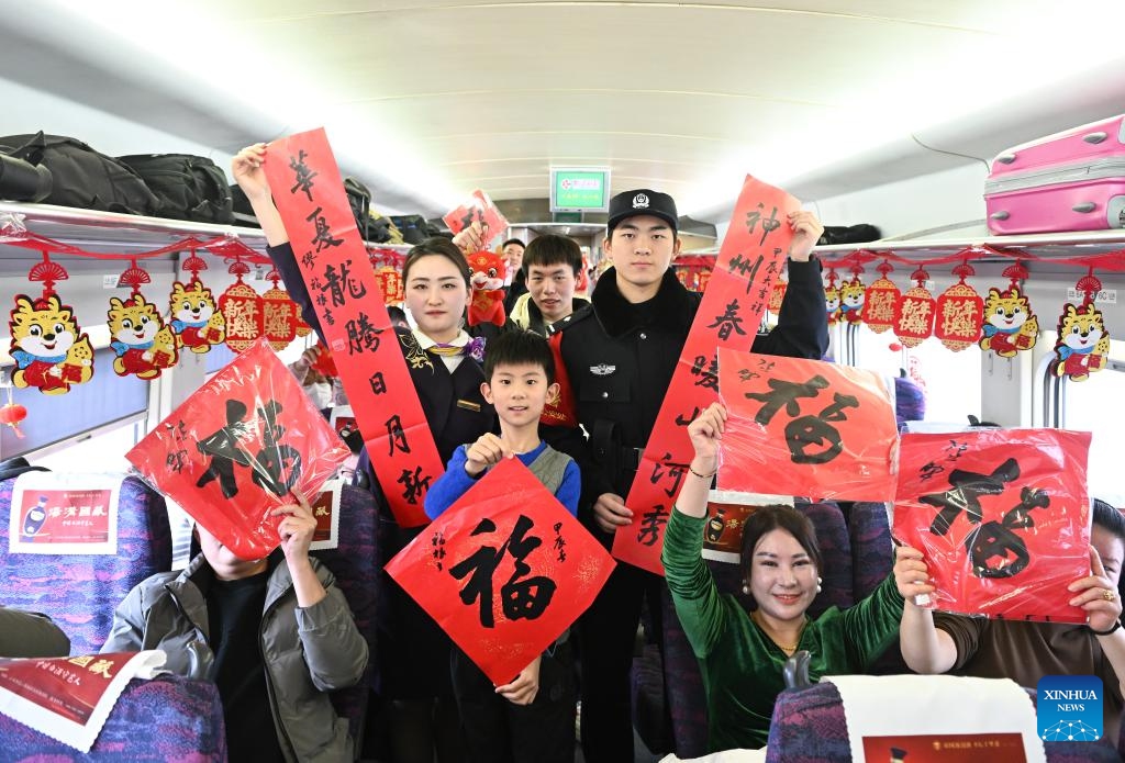 Staff members and passengers pose for a photo onboard G7575 bullet train, Jan. 29, 2024. A series of traditional cultural activities, such as opera performance and paper cutting show, were held on the bullet train on Monday. China officially ushered in its largest annual population migration on Jan. 26. The 40-day travel surge, also known as chunyun, will see hundreds of millions of people return home and reunite with their friends and families.(Photo: Xinhua)