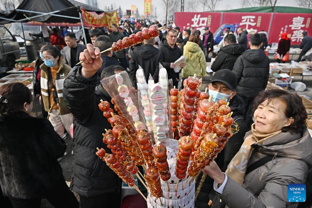 People buy Tanghulu, a traditional Chinese snack of candied fruits, at the Poli Market in Qingdao Xihai'an (West Coast) New Area in Qingdao, east China's Shandong Province, Jan. 29, 2024. With a history of more than 300 years, the Poli Market is a local intangible cultural heritage and one of the biggest traditional markets in eastern Shandong Province.(Photo: Xinhua)