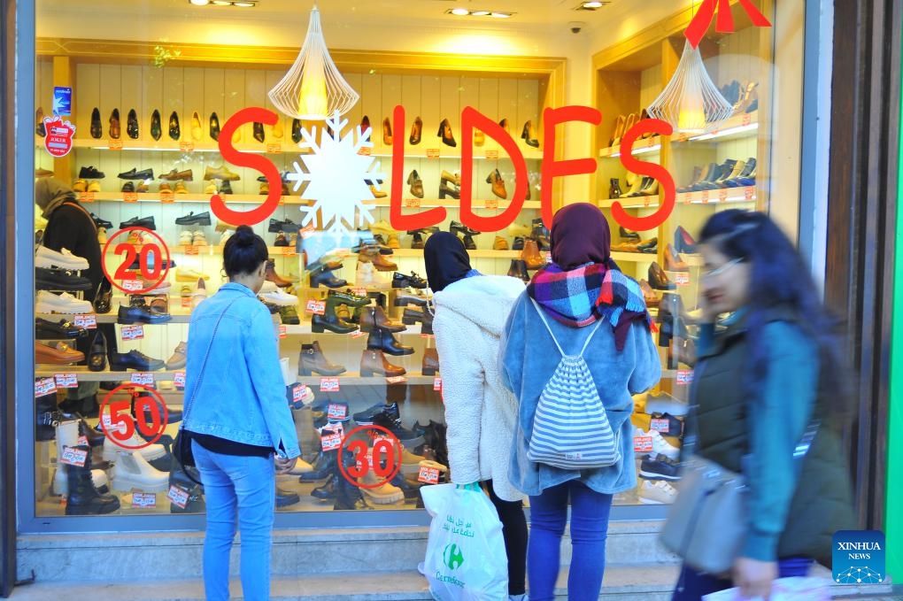 People are seen outside a store with a sale sign in the central business district of Tunis, Tunisia, on Feb. 1, 2024. The annual winter sale season started here on Thursday.(Photo: Xinhua)