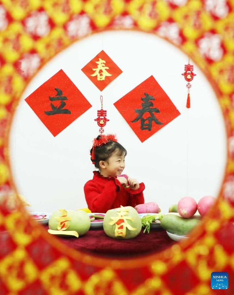 A child bites a radish slice, which is called Yaochun, a ritual expressing the wish for everything to go smoothly on the day of Lichun, meaning the beginning of spring, the first solar term in the traditional Chinese lunar calendar, in Tangshan, north China's Hebei Province, Feb. 4, 2024. (Photo by Zhu Dayong/Xinhua)