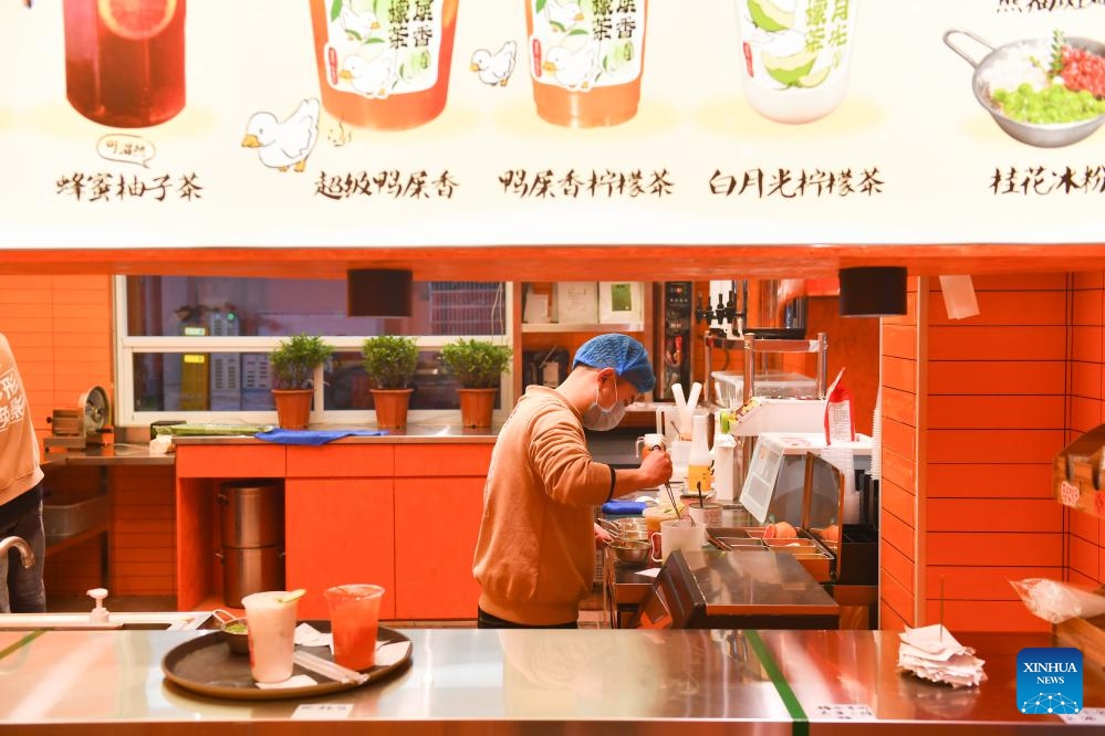 A staff member prepares a beverage at a stall in a night market selling street food in Changsha, central China's Hunan Province, Feb. 4, 2024. To attract more visitors, stalls in this night market are making innovations such as developing new products and promoting via social media.(Photo: Xinhua)