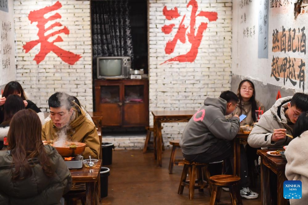 People dine at a stall in a night market selling street food in Changsha, central China's Hunan Province, Feb. 4, 2024. To attract more visitors, stalls in this night market are making innovations such as developing new products and promoting via social media.(Photo: Xinhua)