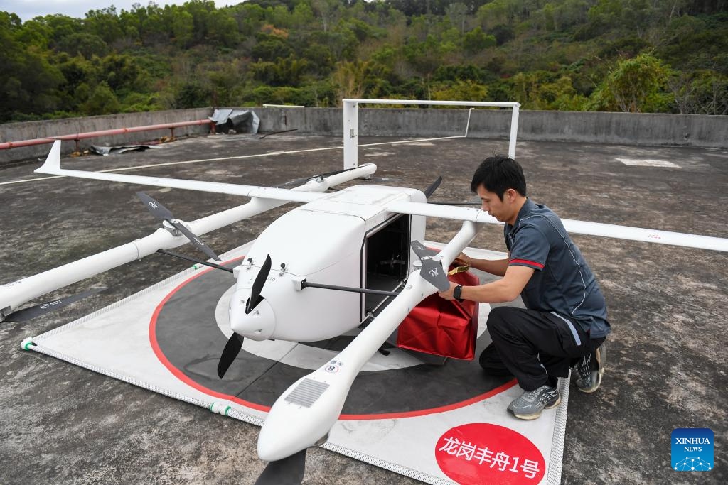 A courier of SF Express takes seafood package from a drone in Longgang District of Shenzhen, south China's Guangdong Province, Feb. 5, 2024. A drone delivery route for seafood has been put into operation between Nan'ao Shuangyong Pier in the east of Shenzhen and the city's Longgang District. The drones take off with up to 20 kilograms load and the seafood will be delivered to local couriers and finally reach the customers.(Photo: Xinhua)