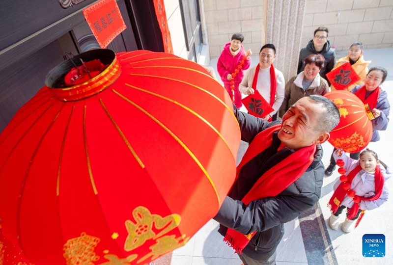 A villager who has just moved into a new house hangs a lantern outside the door in Binhu Village of Changxing County, east China's Zhejiang Province, Feb. 9, 2024. People across the country held various celebrations on Friday, the Chinese Lunar New Year's eve, to welcome the traditional festival. Photo: Xinhua