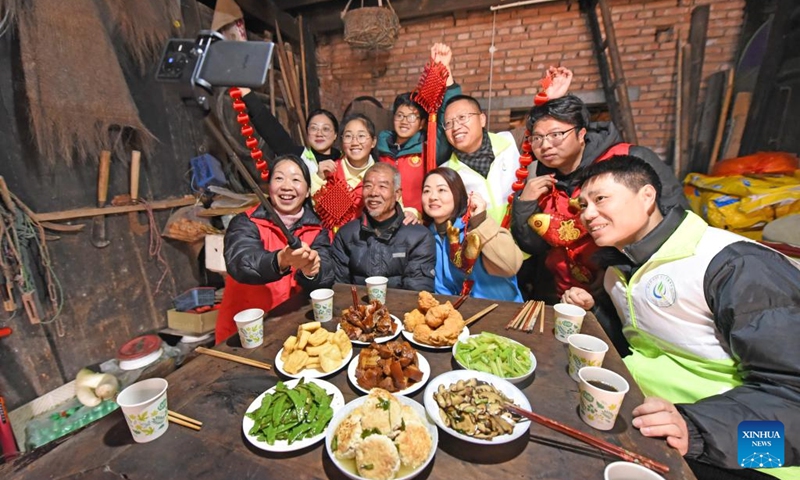 Volunteers from a service center take selfies with an elderly man before they have a reunion dinner in Huanglong Village of Xianju County, Taizhou, east China's Zhejiang Province, Feb. 9, 2024. People across the country enjoy the festive atmosphere with family reunion dinners on the eve of Chinese Lunar New Year on Friday. Photo: Xinhua