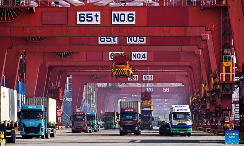 Trucks transport containers at Qingdao Port, east China's Shandong Province, Feb. 11, 2024. The Qingdao port is busy handling goods for export during the Spring Festival holiday. (Xinhua/Li Ziheng)