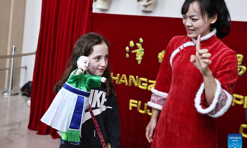 A girl tries maneuvering a puppet following the guidance of an artist of Zhangzhou Puppet Troupe from southeast China's Fujian Province at the City of Architecture and Heritage Museum in Paris, France, Feb. 10, 2024. (Xinhua/Gao Jing)